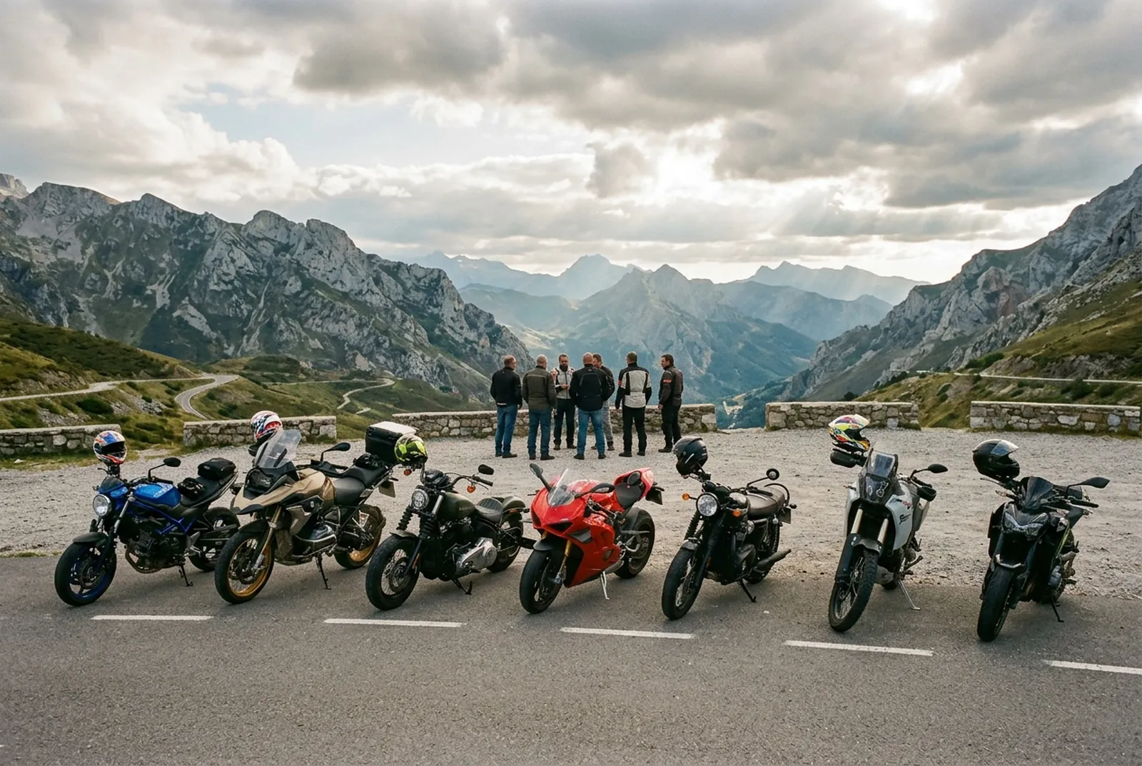 Motos de distintos estilos aparcadas en un mirador de montaña y sus moteros charlando al fondo